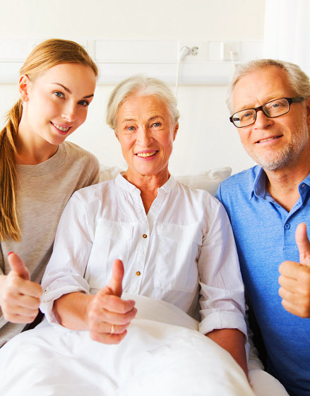 female caregiver and senior couple doing thumbs up