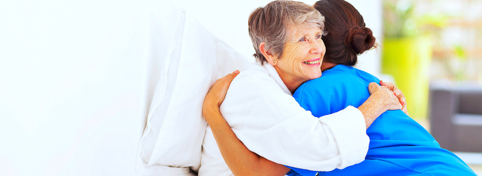 senior woman and female caregiver hugging